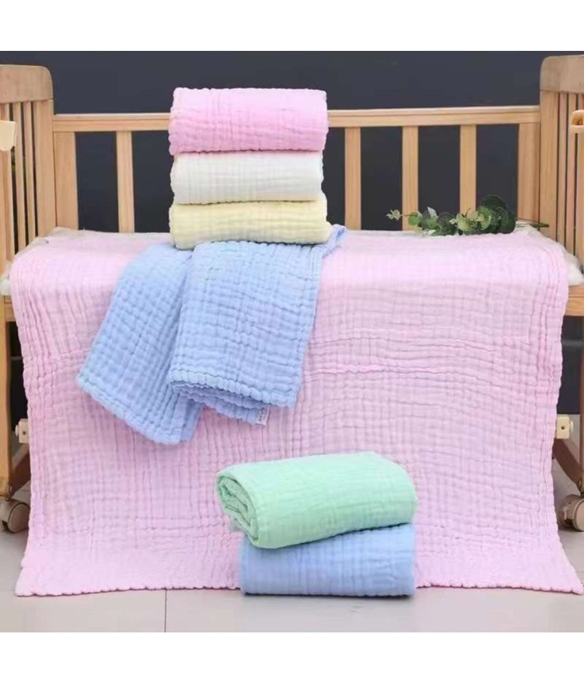 Stack of folded cotton baby bath towel in various colors on a crib